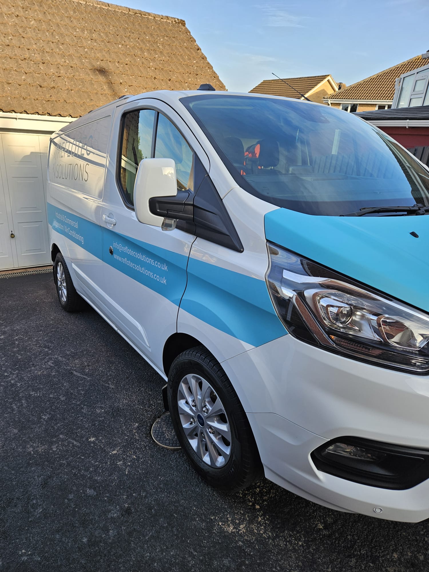 Liveried white and blue work van cleaned outside a house