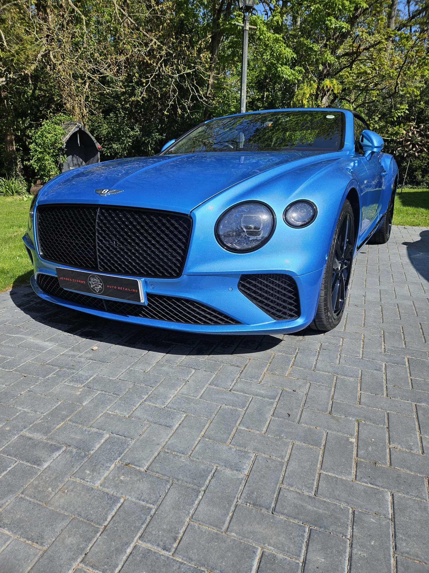 Blue Bentley Continental convertible detailed on a block paved driveway