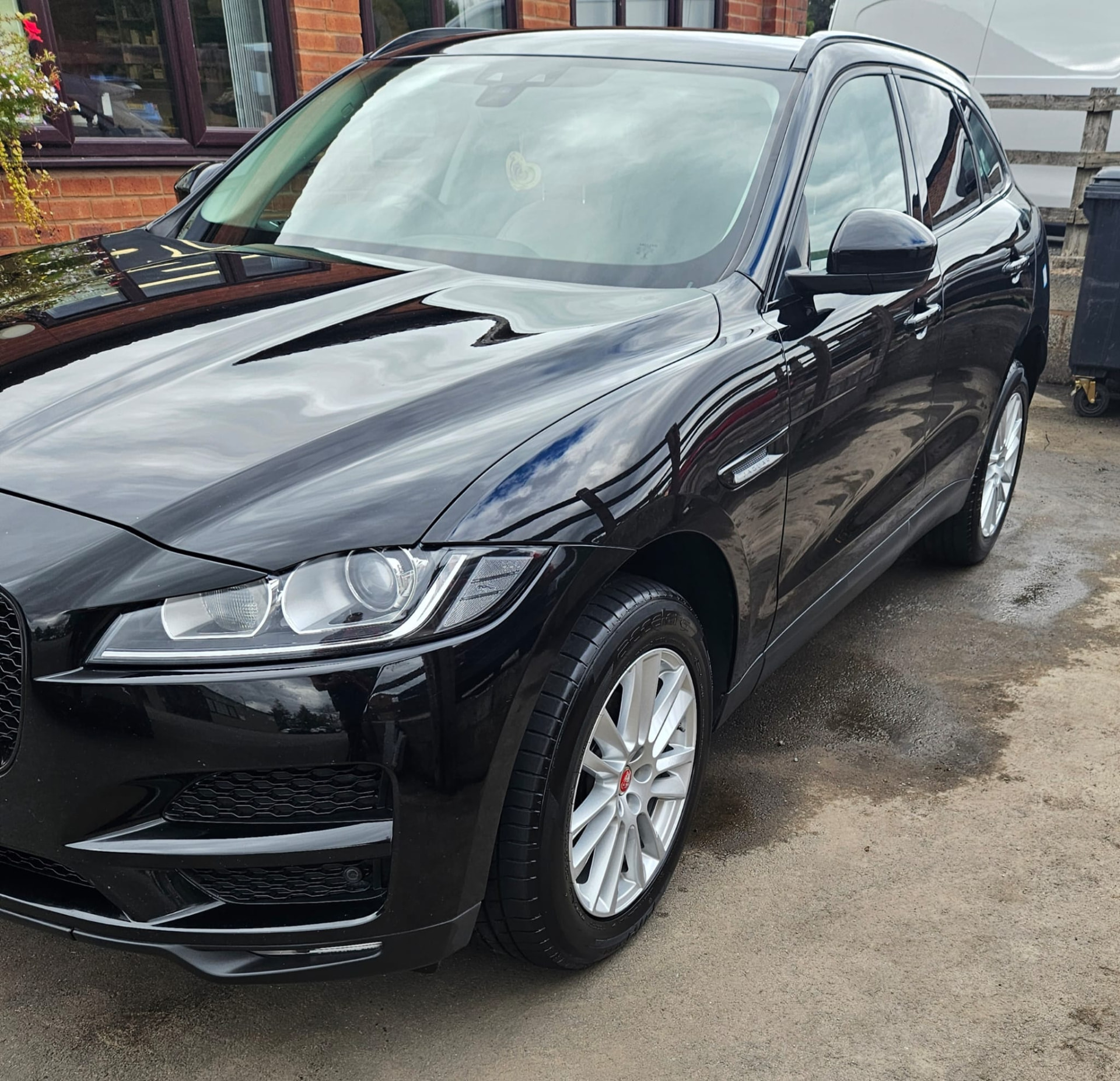 Glossy black Jaguar SUV showing reflections across its bonnet and side panels
