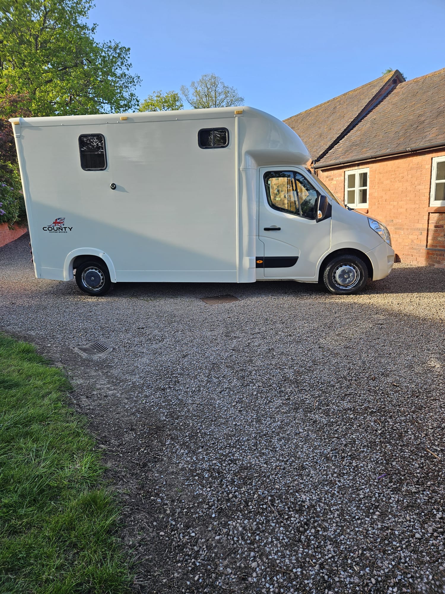 White horsebox cleaned on a gravel driveway