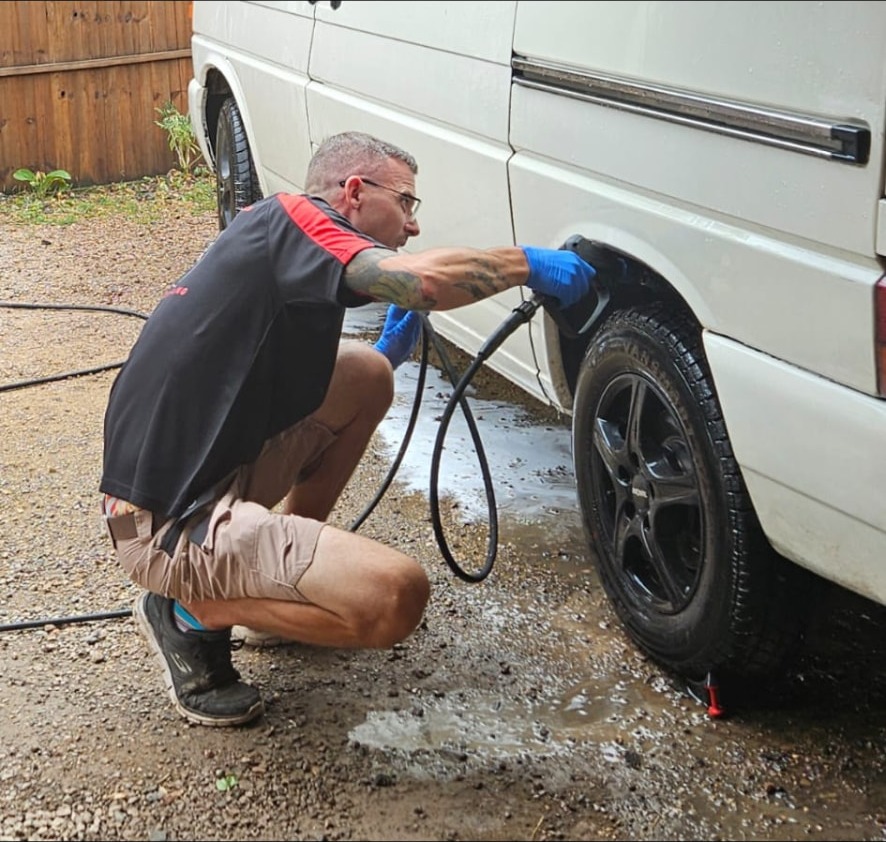Chris washing a white van wheel arch on location